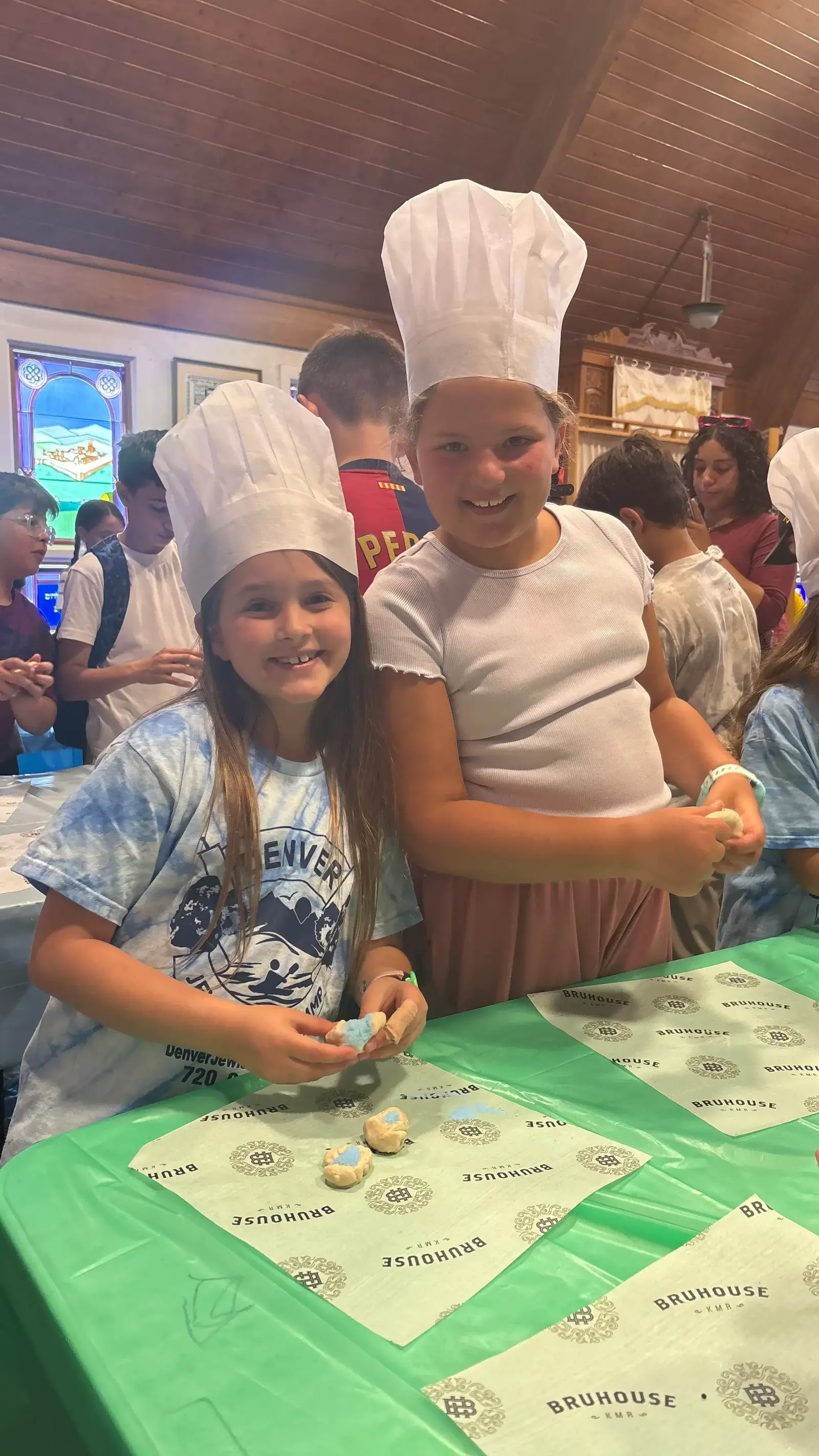 Campers in chef hats shaping challah dough together